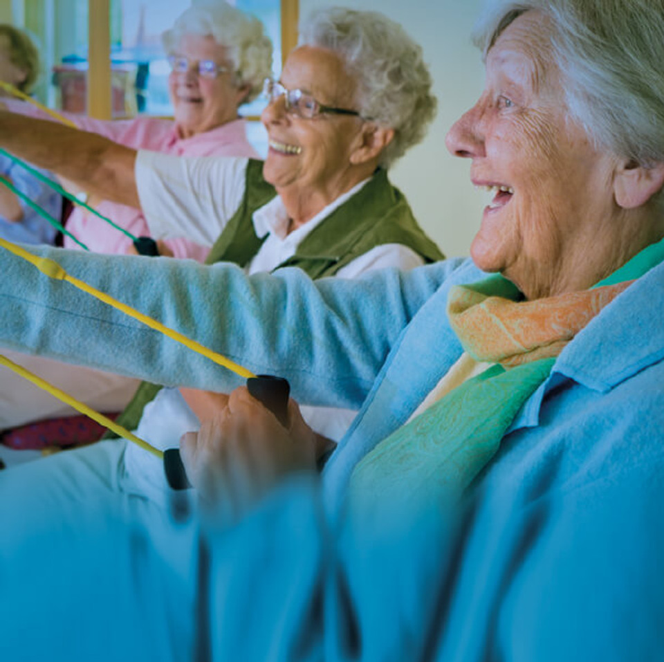 En grupp äldre kvinnor som tränar med gummiband.